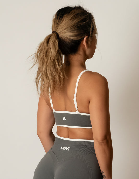 SQWT seamless dark grey sports bra with white contrast for women. Medium support gym bra designed to lift and enhance breasts. Ideal for workouts