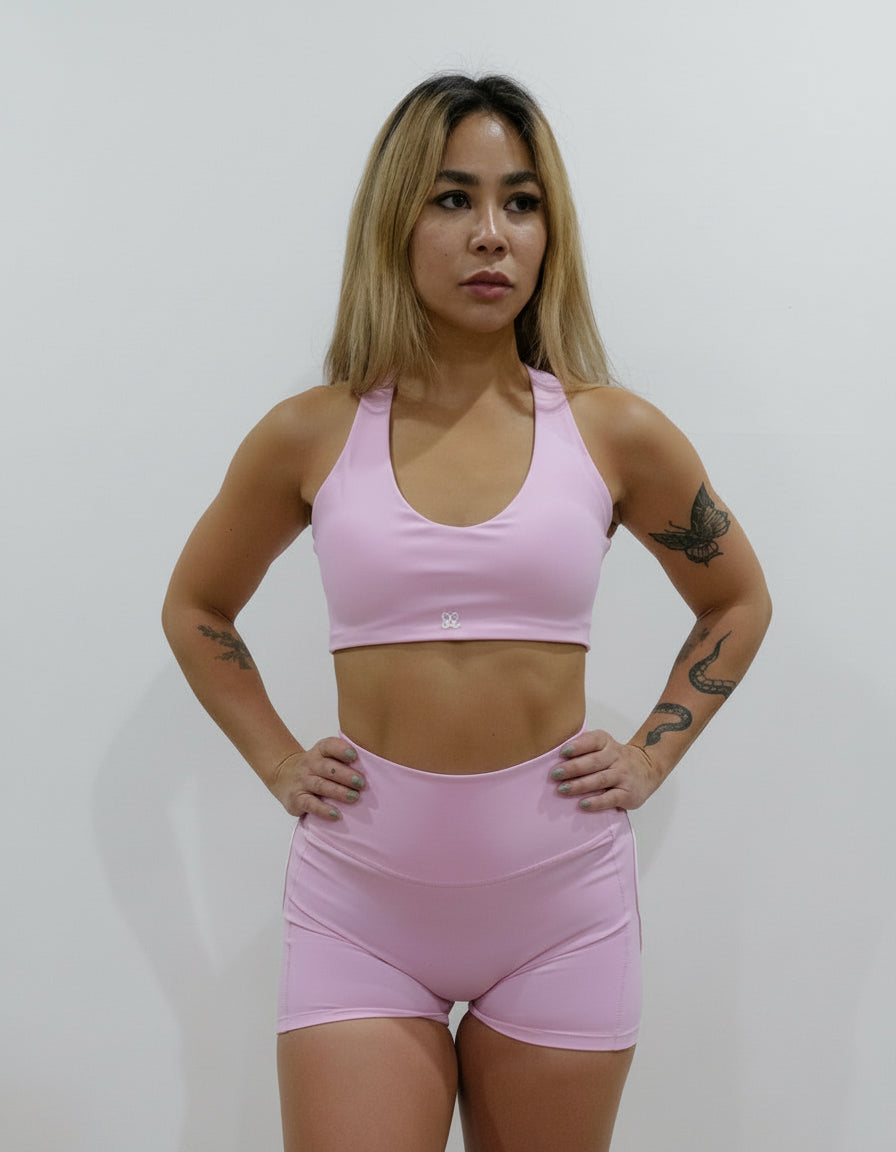 Seamless high-waisted gym shorts in baby pink, featuring a wide V-shaped back waistband with white contrast piping/seaming that enhances the booty shape.