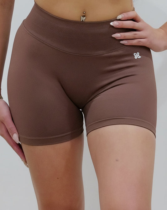 Seamless high-waisted gym shorts in dark brown, featuring a wide V-shaped back waistband and subtle seam detailing designed for an invisible booty lift.