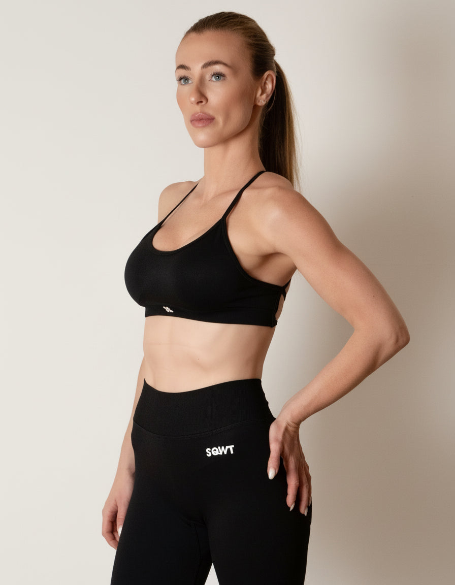Black sports bra with thin straps, featuring a cross-back design and supportive front fit, shown on a model from both front and back.