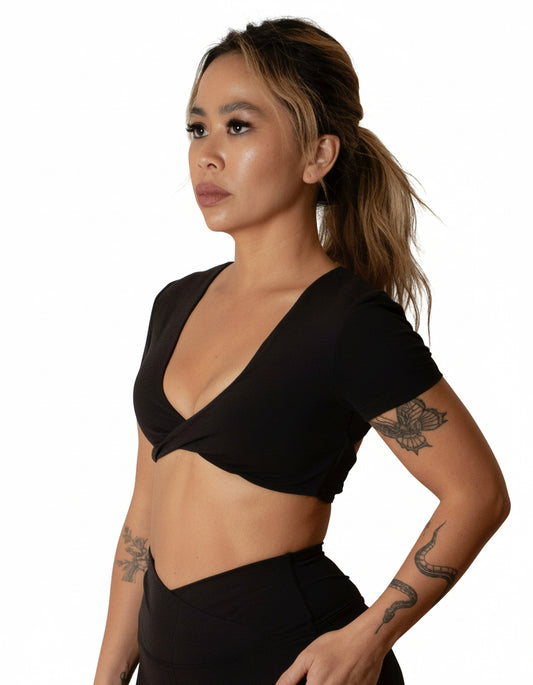 Black short-sleeve crop top/bra top with a twisted knot front and back, open cut-out back, and a deep V-neckline. Ideal for women's activewear, gym, and yoga.
