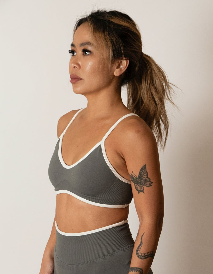 SQWT seamless dark grey sports bra with white contrast for women. Medium support gym bra designed to lift and enhance breasts. Ideal for workouts