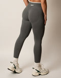 Dark grey seamless leggings with white piping featuring a supportive high waist, invisible scrunch butt, and butt lifting compression, perfect for gym, squat proof workouts, and fitness.