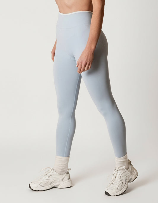 Baby blue seamless leggings with white piping featuring a supportive high waist, invisible scrunch butt, and butt lifting compression, perfect for gym, squat proof workouts, and fitness.