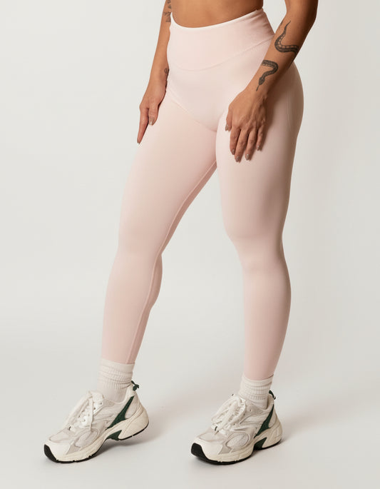 Baby pink seamless leggings with white piping featuring a supportive high waist, invisible scrunch butt, and butt lifting compression, perfect for gym, squat proof workouts, and fitness.