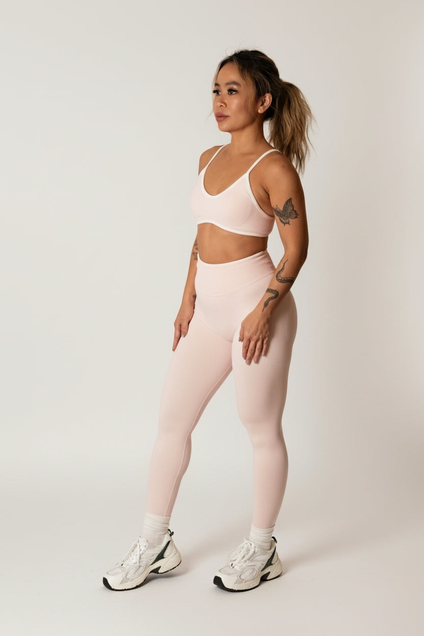 Baby pink seamless leggings with white piping featuring a supportive high waist, invisible scrunch butt, and butt lifting compression, perfect for gym, squat proof workouts, and fitness.