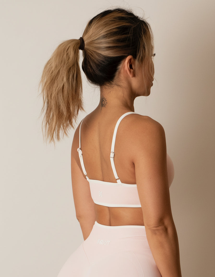 SQWT seamless baby pink sports bra with white contrast for women. Medium support gym bra designed to lift and enhance breasts. Ideal for workouts