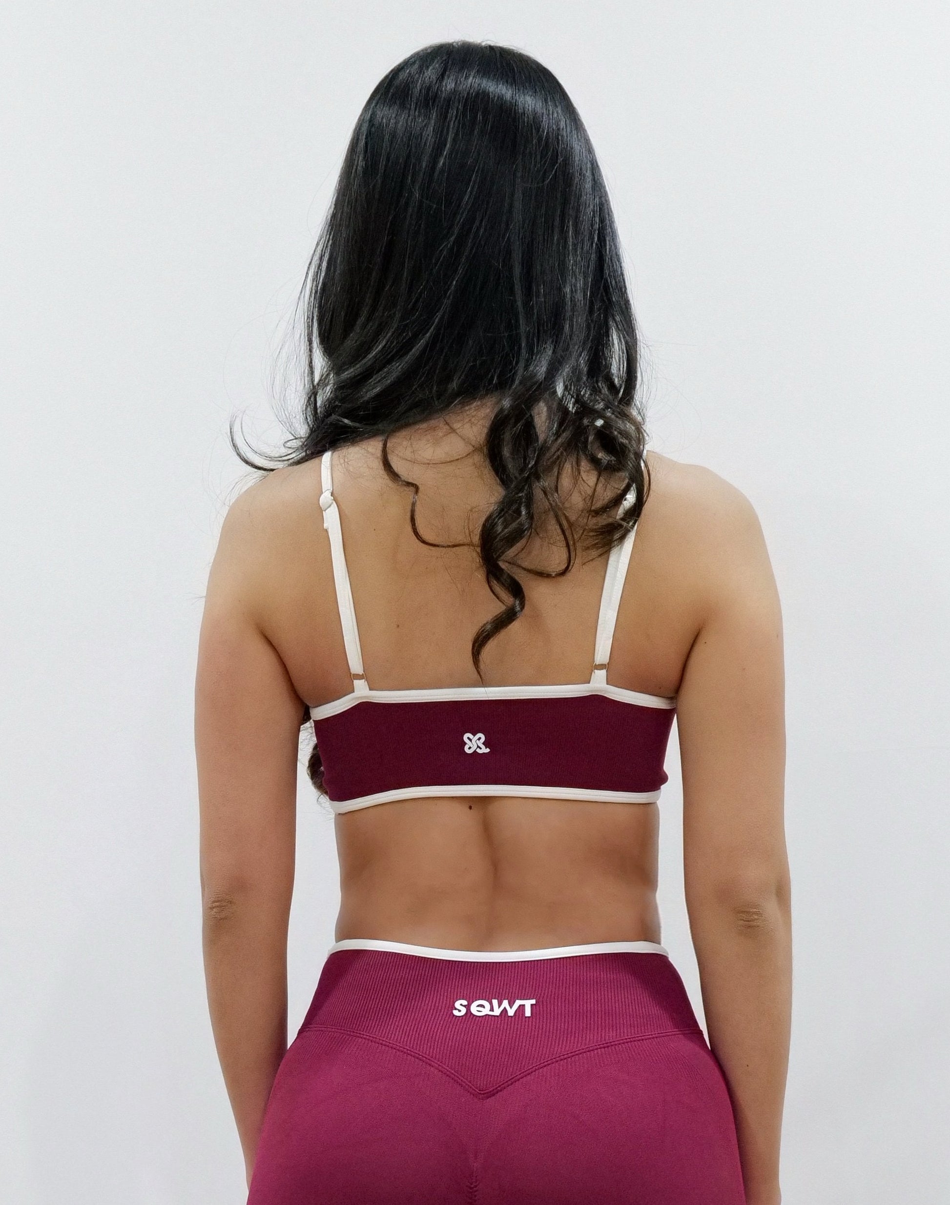 SQWT seamless red wine sports bra with white contrast for women. Medium support gym bra designed to lift and enhance breasts. Ideal for workouts