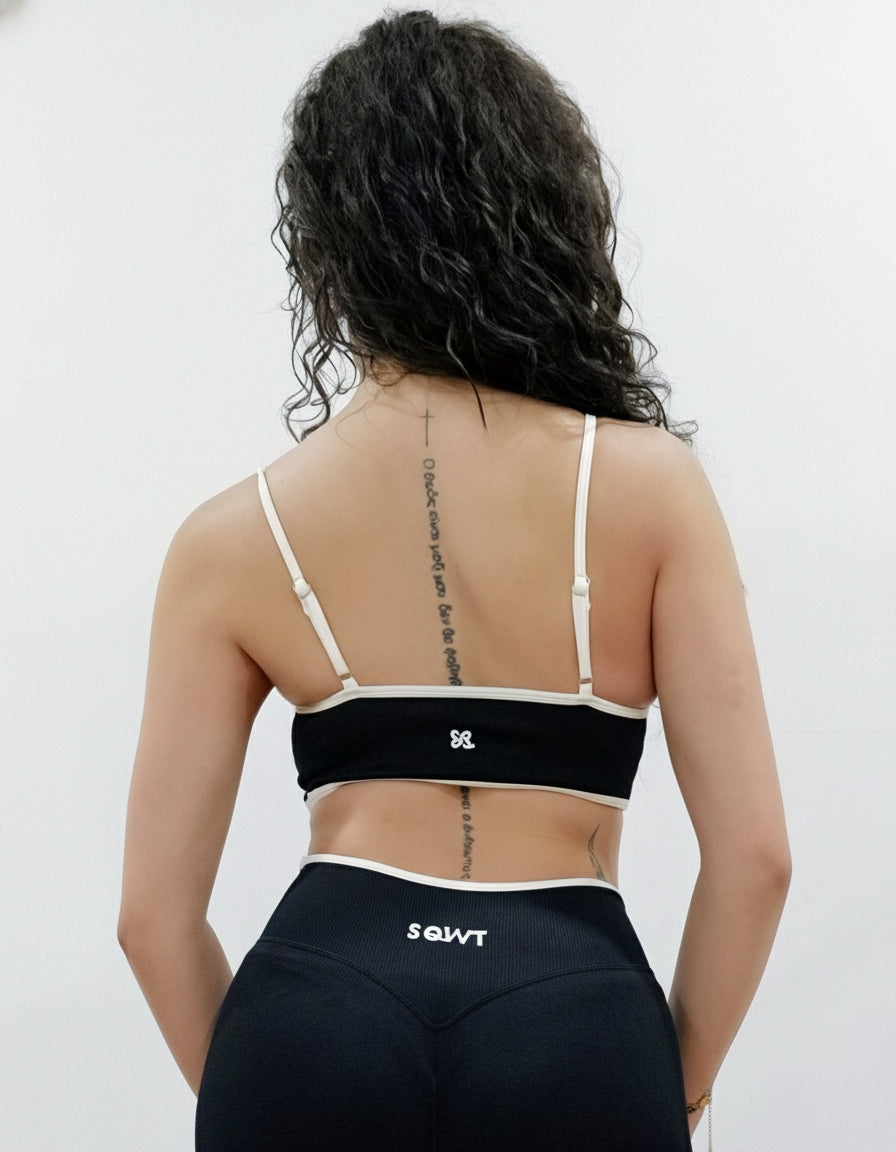 SQWT seamless black sports bra with white contrast for women. Medium support gym bra designed to lift and enhance breasts. Ideal for workouts