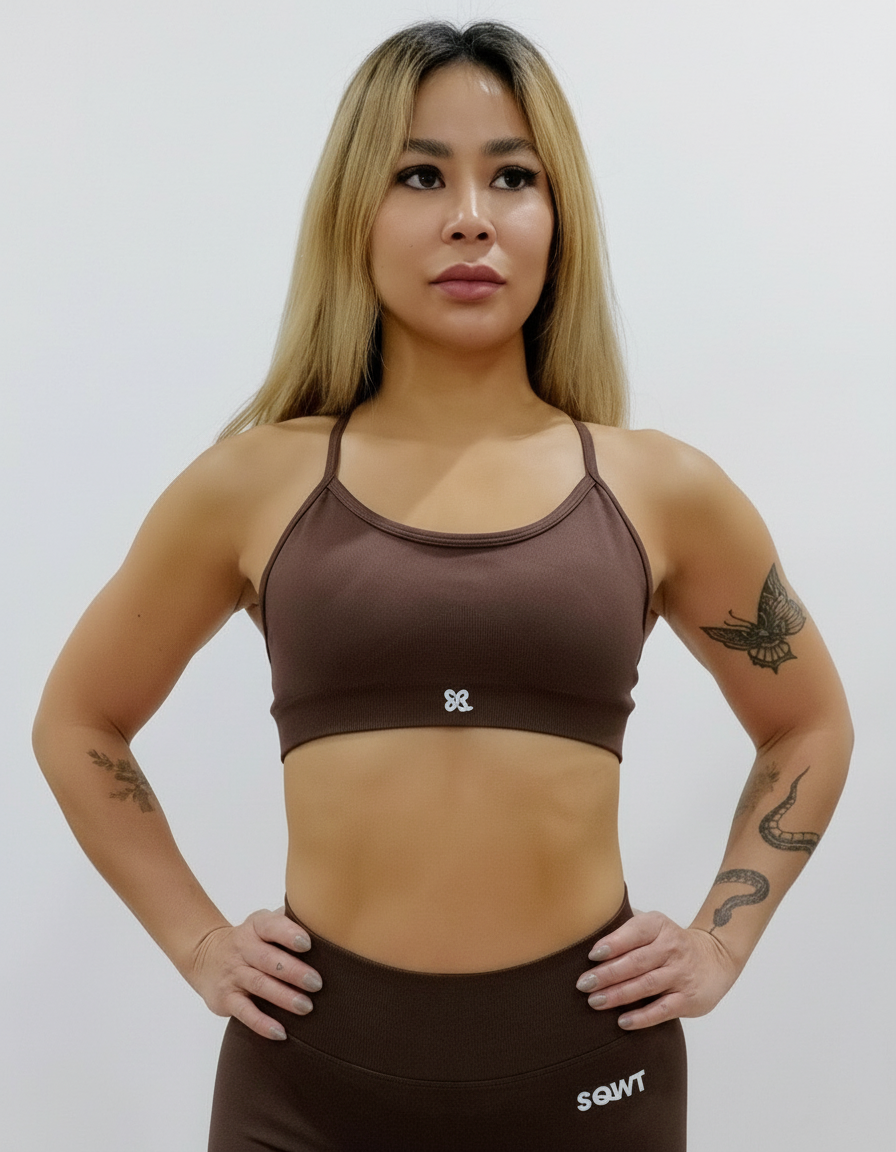 Dark brown sports bra with thin straps, featuring a cross-back design and supportive front fit, shown on a model from both front and back.