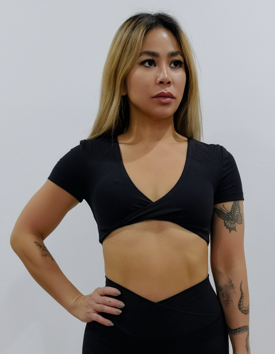 Black short-sleeve crop top/bra top with a twisted knot front and back, open cut-out back, and a deep V-neckline. Ideal for women's activewear, gym, and yoga.