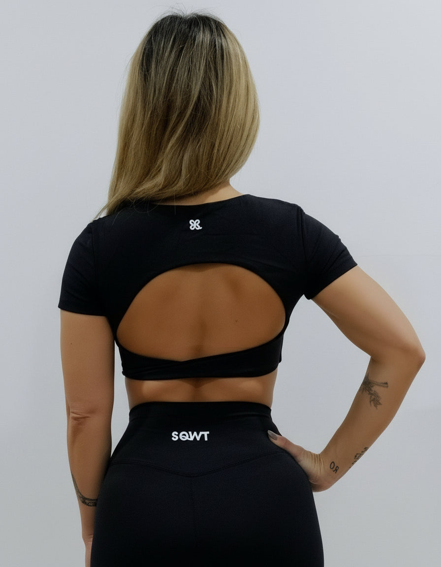 Black short-sleeve crop top/bra top with a twisted knot front and back, open cut-out back, and a deep V-neckline. Ideal for women's activewear, gym, and yoga.