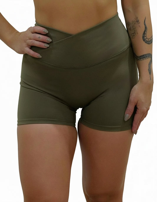 Olive green seamless high-waist shorts with flattering V-shaped crossover waistband, best for women's studio sessions, yoga, and athleisure.