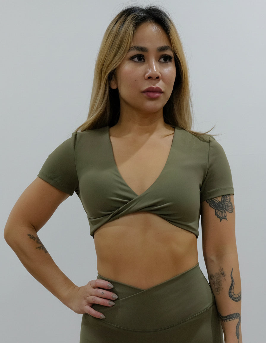 Olive green short-sleeve crop top/bra top with a twisted knot front and back, open cut-out back, and a deep V-neckline. Ideal for women's activewear, gym, and yoga.