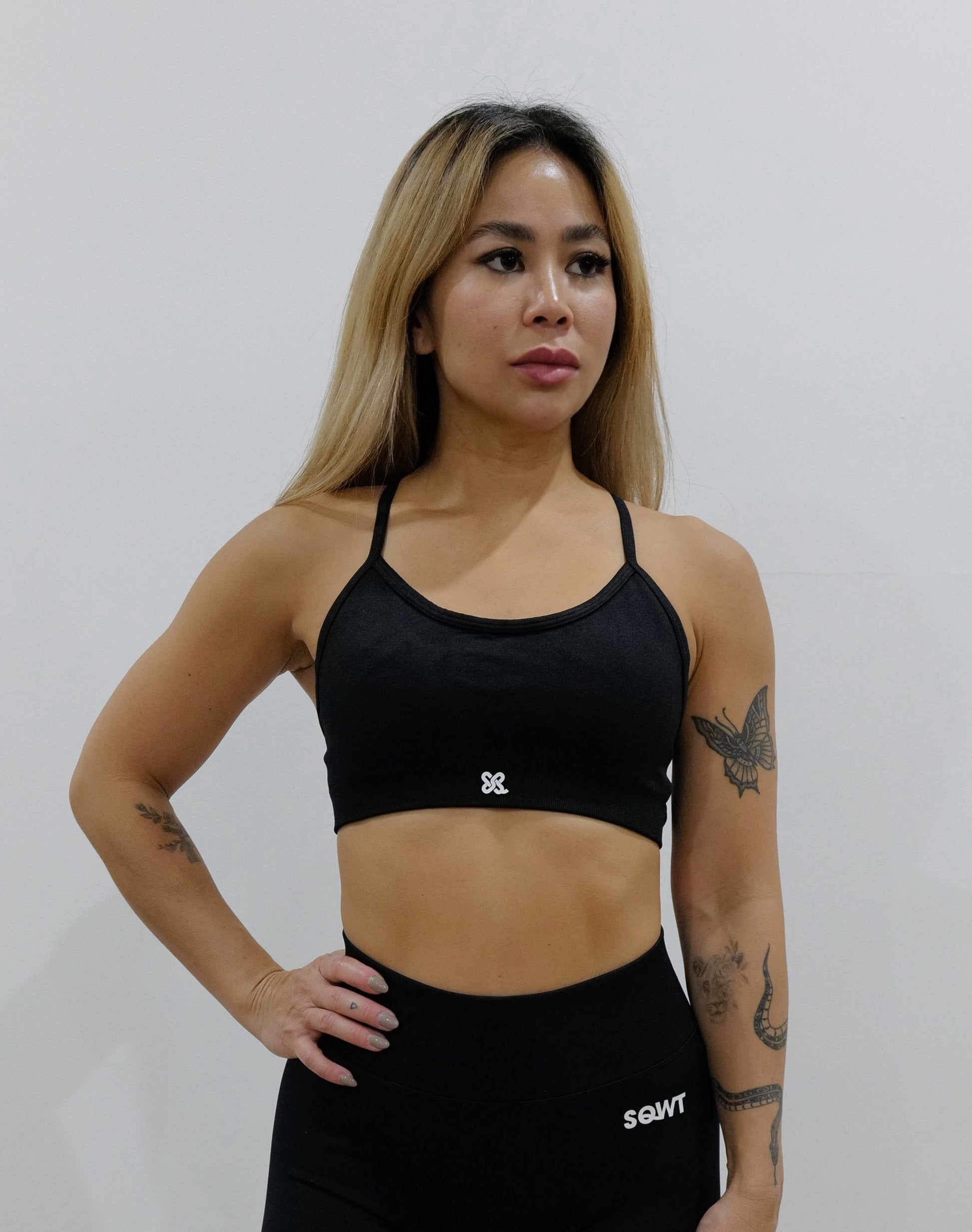 Black sports bra with thin straps, featuring a cross-back design and supportive front fit, shown on a model from both front and back.