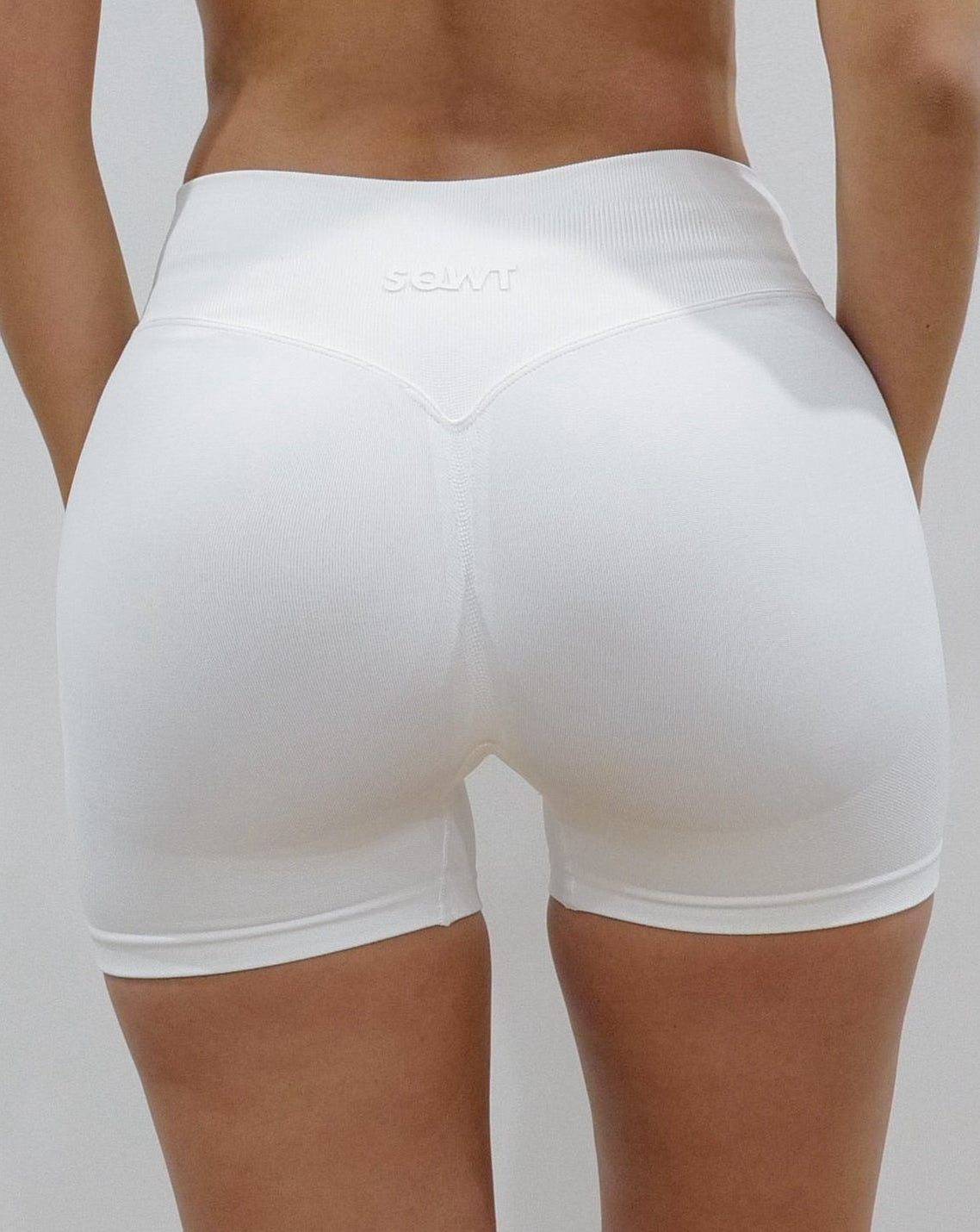 White seamless high-waisted scrunch gym shorts with a V-shaped back waistband.