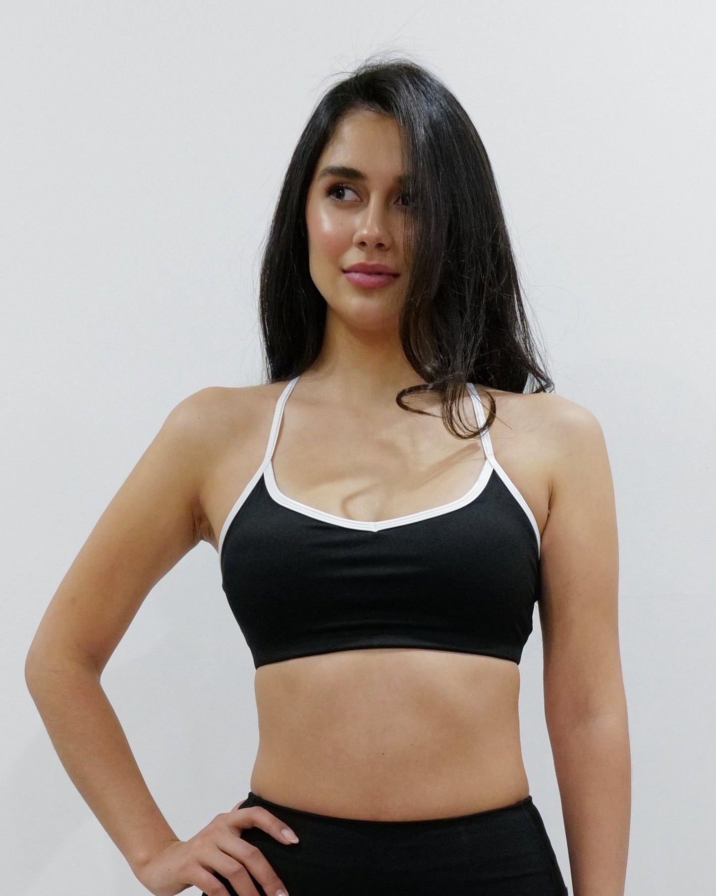 SQWT ContourHeart  Bra in Black, a light-compression workout bra for women with white trim, scoop neck, and unique Y-back strap design for yoga, Pilates, and everyday comfort.