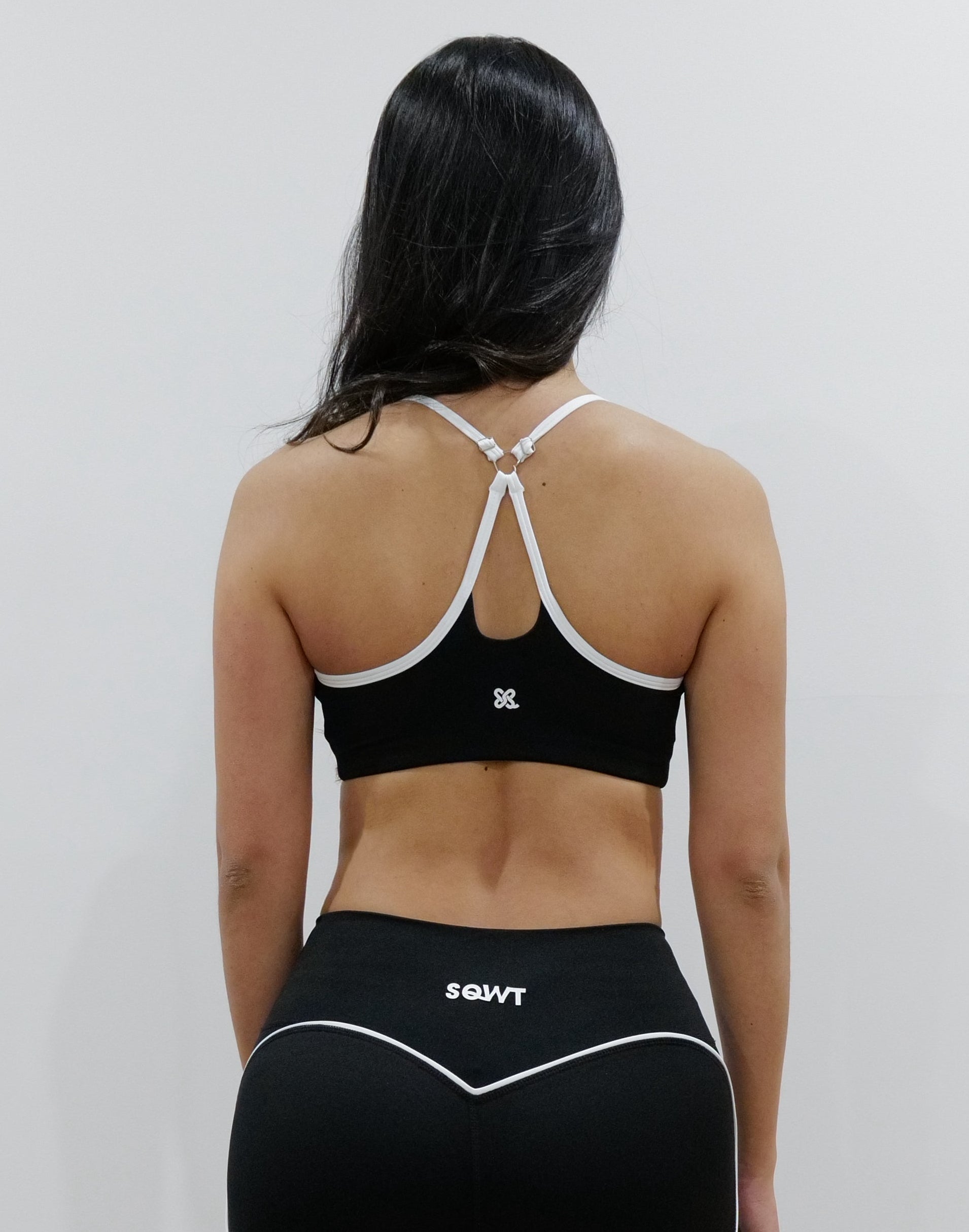 SQWT ContourHeart  Bra in Black, a light-compression workout bra for women with white trim, scoop neck, and unique Y-back strap design for yoga, Pilates, and everyday comfort.