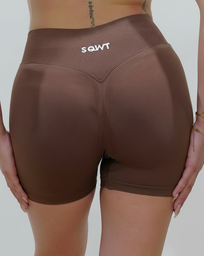 Seamless high-waisted gym shorts in dark brown, featuring a wide V-shaped back waistband and subtle seam detailing designed for an invisible booty lift.